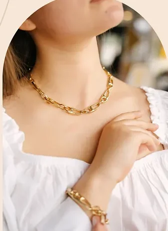 A gold chain necklace at the collarbone.