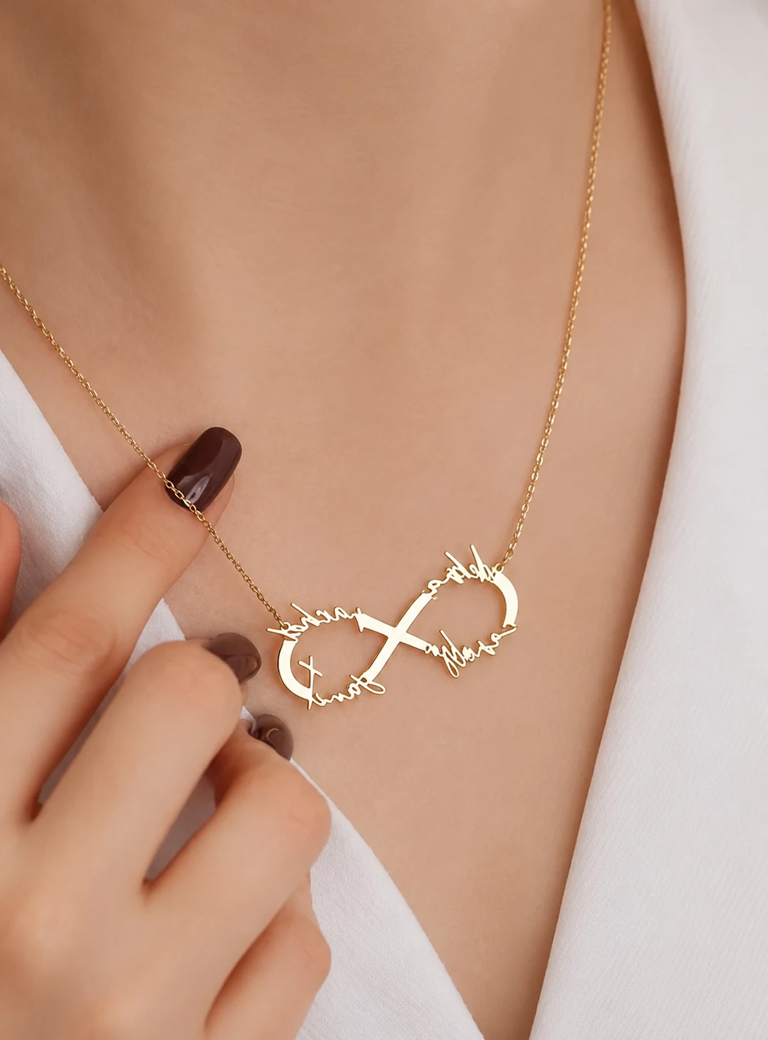 A hand at the collarbone, wearing a fine gold chain.
